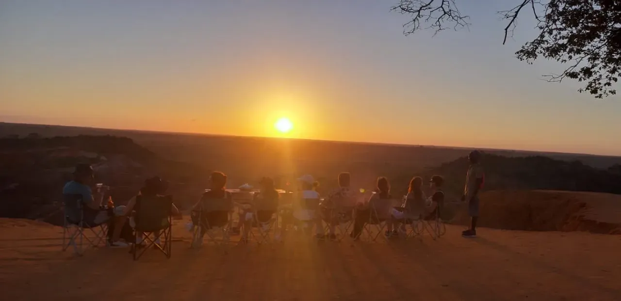 Il gruppo degli ospiti seduto in fila sul crinale, a guardare il sole che scende.