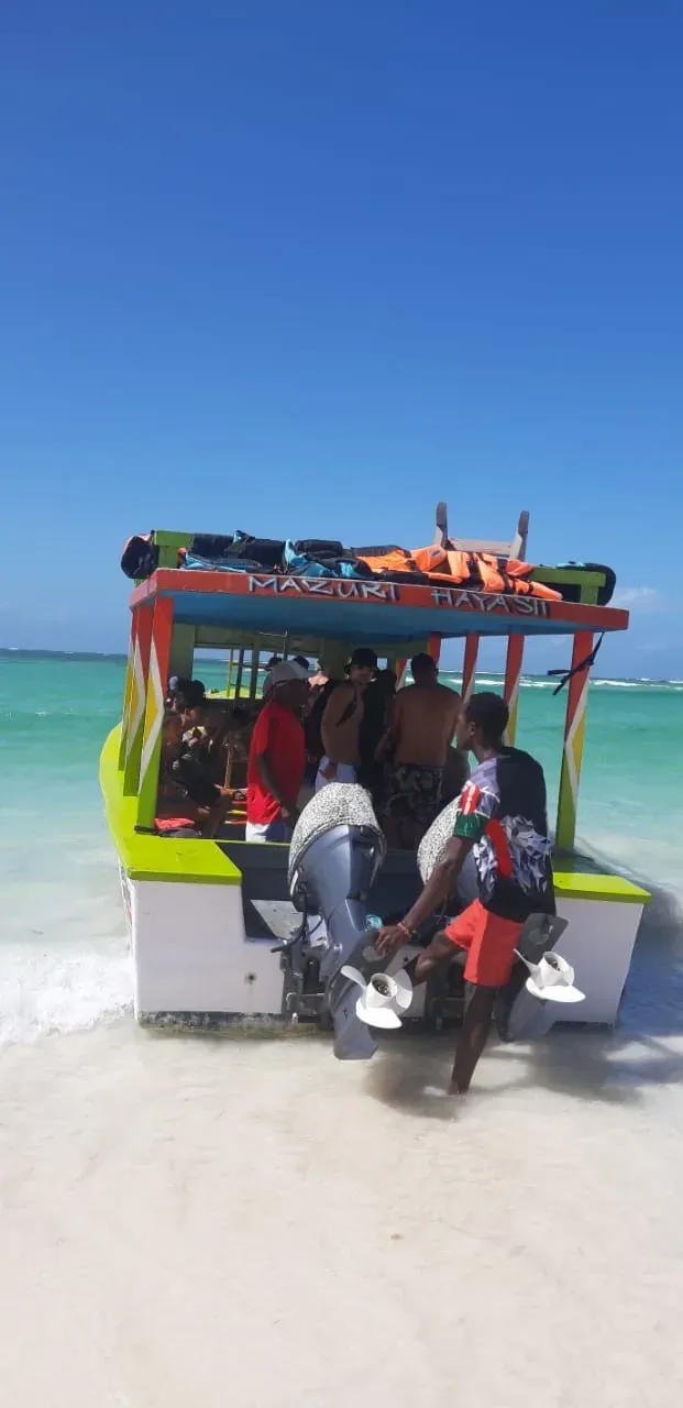 La barca colorata dell'escursione ferma sul banco di sabbia, con gli ospiti a bordo e l'acqua turchese intorno.